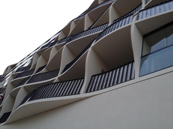 Panelák s oblými balkónmi, na ktorých sú sklenené a kovové zábradlia.jpg